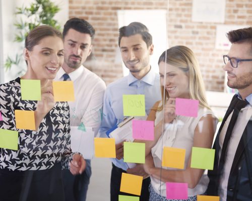 Team behind glass with colorful papers